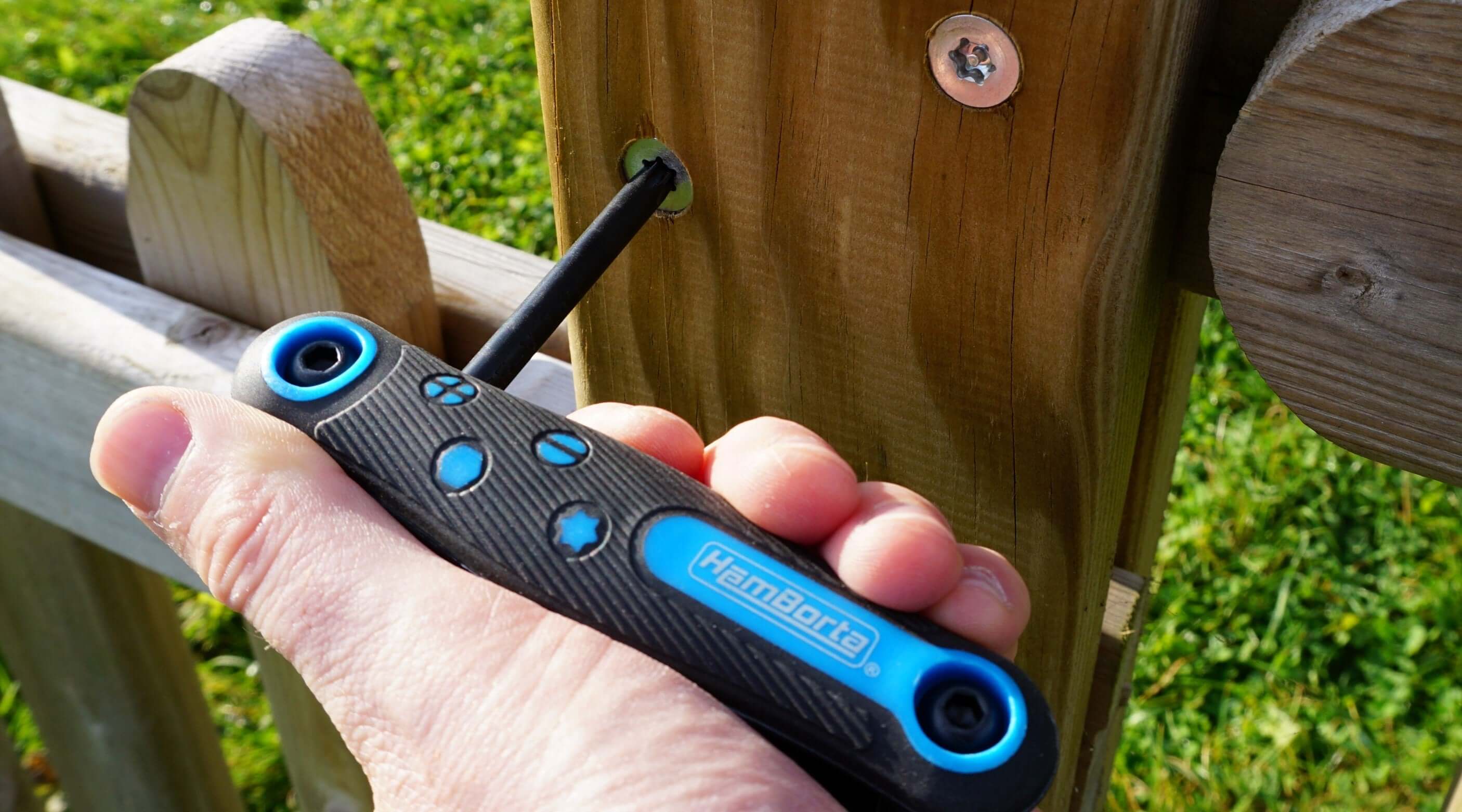 Person using a star key set on a wooden fence, demonstrating the functionality of Torx screws.
