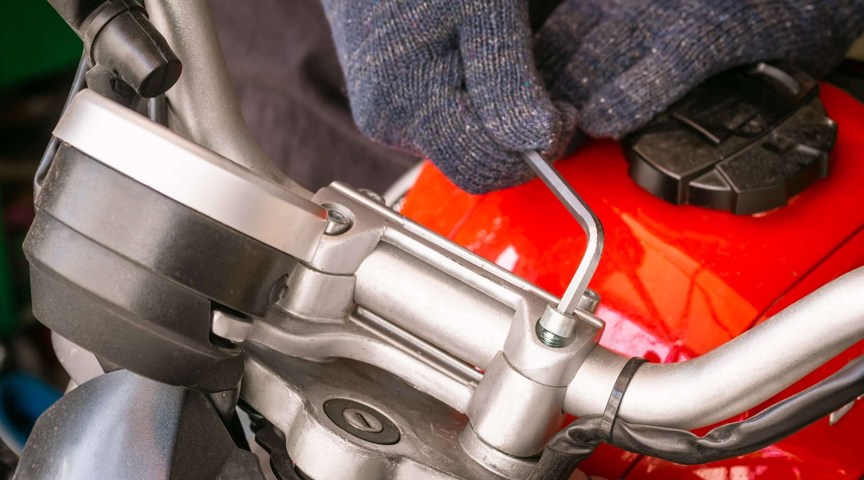 A person using an Allen key on a motorcycle handlebar, showcasing the tool in action.