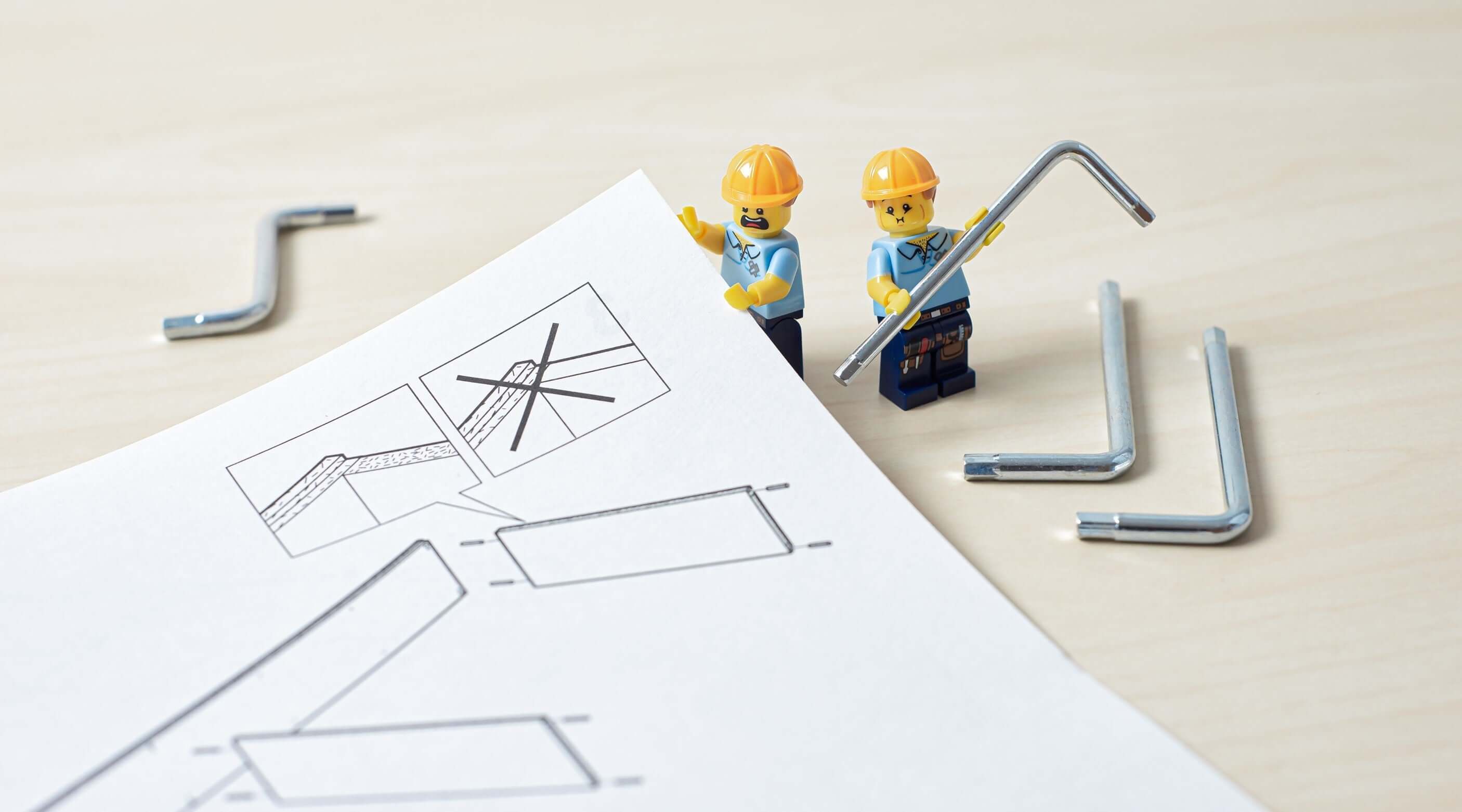 Two construction toy figures beside Allen keys and assembly instructions on a table.