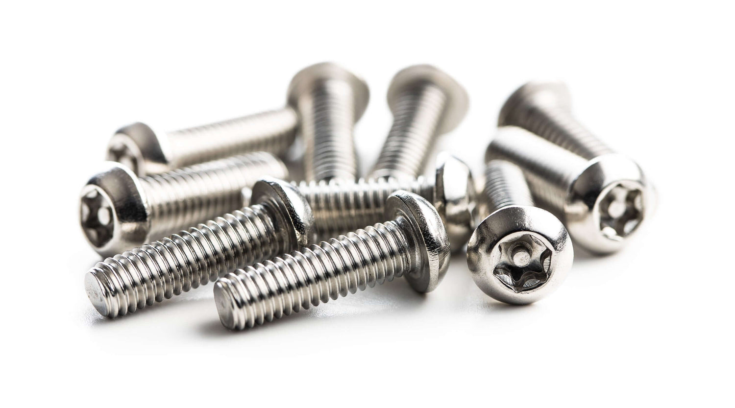 Close-up of multiple silver tamper-resistant Torx screws arranged on a white surface.