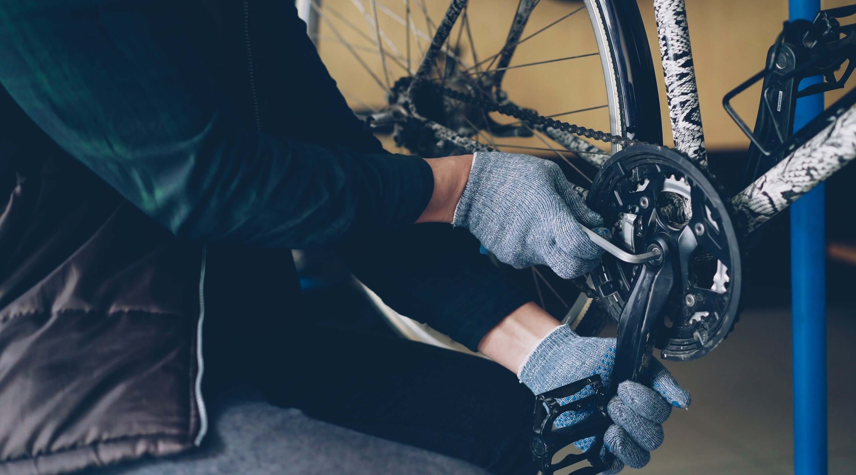 Person using an Allen key set to adjust a bicycle gear while wearing gloves.